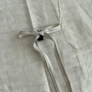 Détail du nœud papillon à carreaux crème avec petite pince à cheveux noire en plastique