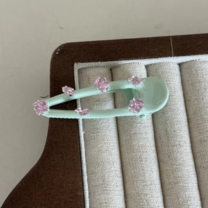 Detail of mint green hair clip with sparkling pink rhinestones on a display tray