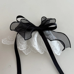 Detail of elegant black organza bow hairpin with white lace trim and satin ribbons