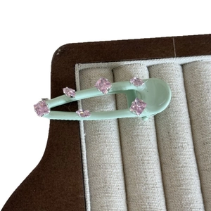 Mint green matte hair clip with pink crystal embellishments on white background