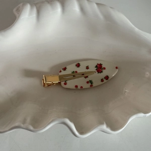 Détail d'une pince à cheveux à motifs de roses rouges avec un fermoir en métal doré