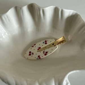 Détail d'une pince à cheveux de style français avec motifs cerises sur assiette
