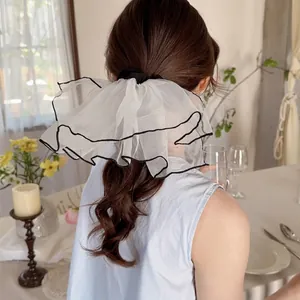 Elegant white organza scrunchie with black trim shown on a model ponytail hairstyle