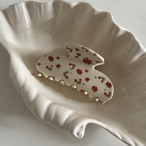 Pince à cheveux vintage française avec motifs de roses et strass sur un plat décoratif