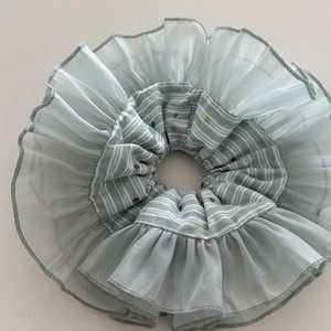 Detail of mint green organza scrunchie with floral embroidery and striped inner fabric