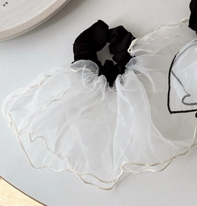 Close-up of white mesh organza scrunchie with elegant black trim and wavy edge detail