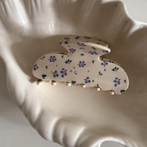 Détails de la pince à cheveux crème avec motifs floraux bleus et décorations en strass