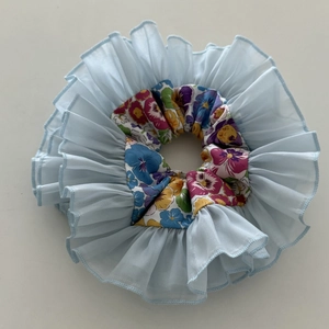 Close-up of light blue organza and floral print fabric scrunchie with layered texture