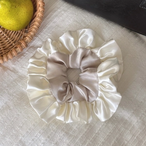 Gros plan sur un chouchou en satin beige et ivoire avec une texture élégante à volants