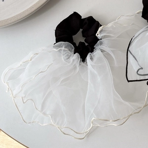 Elegant black scrunchie with layered white mesh ruffles for hair styling or wrist wear
