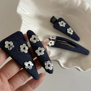 Detail of four-piece denim hair clips set with silver flower metal charms and duckbill grip