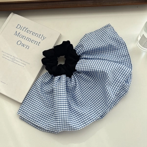 Detail of blue and white gingham hair scrunchie with soft ruffled fabric texture