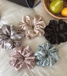 Macro view of silky satin scrunchies in cream champagne silver pink and blue colors