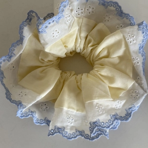 Detailed macro view of yellow and white lace hair scrunchie with blue embroidery