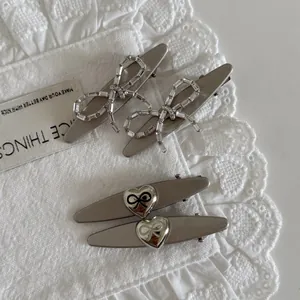 Set of four silver bow hair clips with rhinestones and heart charms on lace fabric