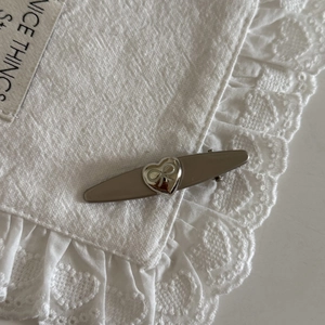 Close-up of heart-shaped bow buckle on a dark beige hair clip with lace background