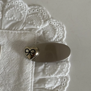 Close-up of vintage heart hair clip with black bow on elegant white lace fabric
