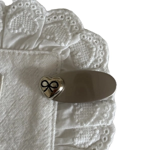 Silver bow heart hair clip for women with vintage aesthetic on white lace fabric