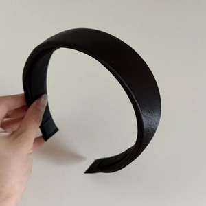 Close-up of a wide black satin headband with soft padding and elegant glossy finish