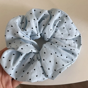 Detail of light blue scrunchie with black heart pattern in soft cotton fabric material