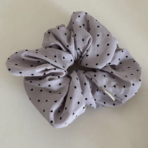 Detailed view of a lavender scrunchie featuring black heart polka dots and ruffled fabric texture