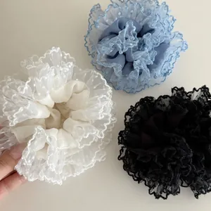Detail of three mesh lace hair scrunchies in white, foggy blue, and black colors