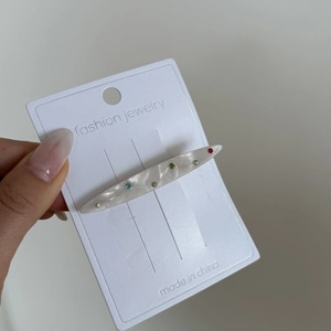Barrette à cheveux en résine marbrée blanche et strass colorés sur carte bijou