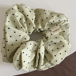 Close-up of light green heart pattern scrunchie featuring a sewn brand label detail