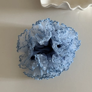 Macro view of light blue mesh hair scrunchie with white polka dots and navy trim