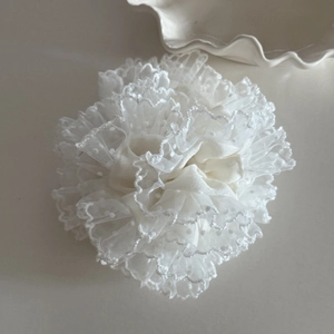 Close-up of white mesh scrunchie with delicate polka dot embroidery and ruffled layers
