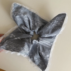 Detail of oversized black and white gingham scrunchie with white floral lace embroidery edge