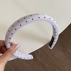 Close-up of light purple fabric headband with black heart pattern and woven label detail
