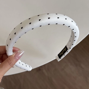 Detail of white padded headband with black heart print and smooth satin texture