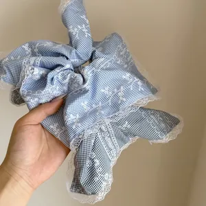 Detail of light blue checkered scrunchie featuring delicate white floral embroidery lace
