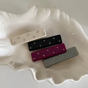 Elegant acetate hair clips set with sparkling rhinestones in four colors on shell tray