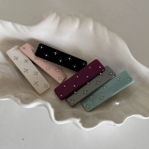 Close-up of rectangular acetate hair clips with sparkling rhinestones in a shell tray