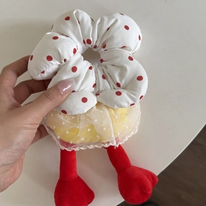 Close-up of fluffy scrunchie featuring red polka dots with lace and plush legs detail