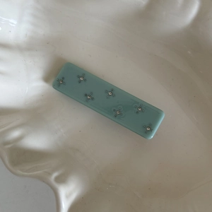 Detail of light blue acetate hair clip with sparkling silver rhinestone floral pattern