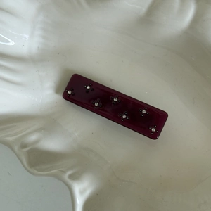 Macro shot of dark purple acetate hair clip featuring delicate rhinestone flower patterns
