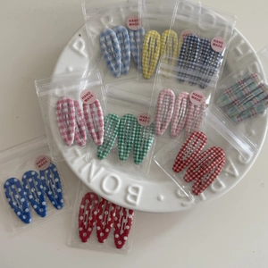Close-up of handmade gingham and polka dot BB hair clips in clear packaging