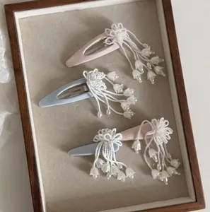 Nahaufnahme von handgefertigten rosa und blauen Maiglöckchen-Haarspangen mit Perlen
