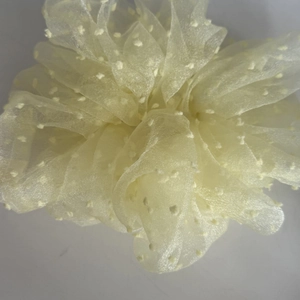 Close-up of light yellow chiffon scrunchie with white polka dots and soft texture