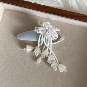 Eleganter Haarclip mit rosa Maiglöckchen-Perlen und floralen Details auf einem Tablett