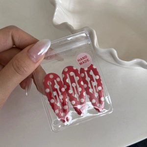 Close-up of three red polka dot hair clips in handmade packaging on a white plate