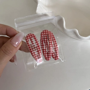 Detail of red and white checkered hair clips in transparent packaging on white background