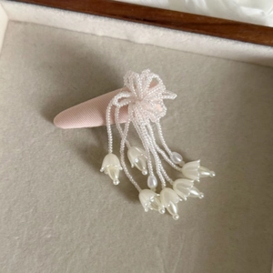 Nahaufnahme der rosa Maiglöckchen Perlenhaarklammer mit Quasten auf einem Samt-Display