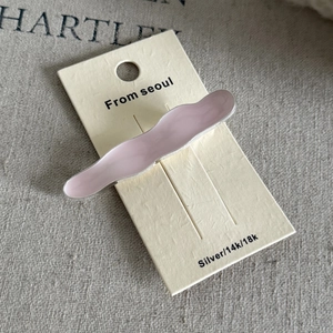 Detail view of wavy pink cream-colored metal hair clip on Seoul display card