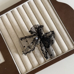 Détail d'une élégante pince à cheveux avec nœud en tulle à pois noirs et strass scintillants