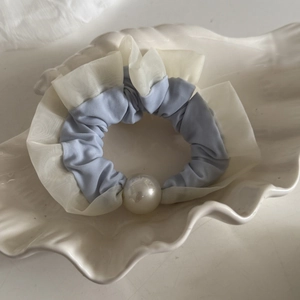 Detailed view of light blue satin and white mesh scrunchie with a large pearl accent