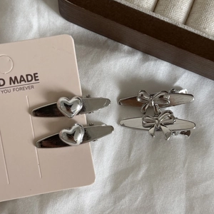 Set of four silver brushed metal hair clips featuring 3D heart and bow designs